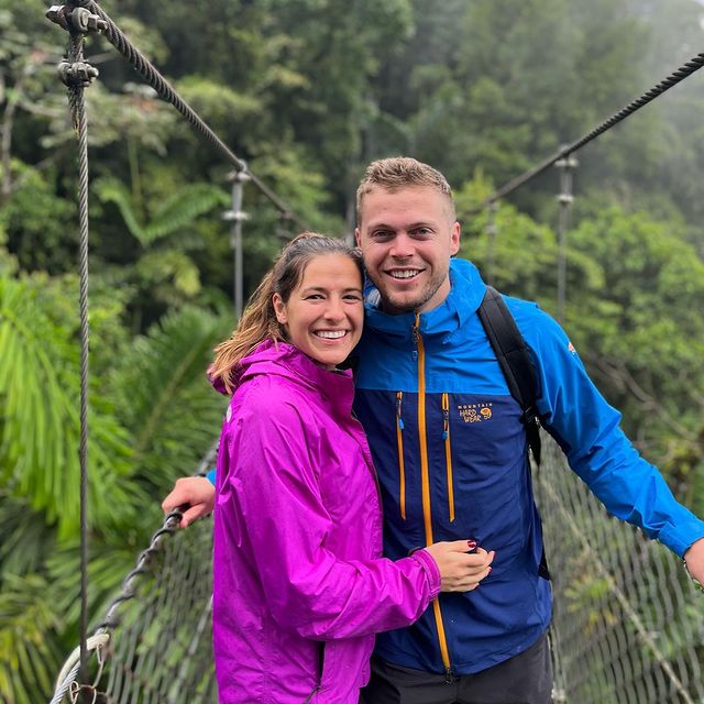 Nico Hoerner and Julia Ditosto standing on a suspension bridge in the jungle.